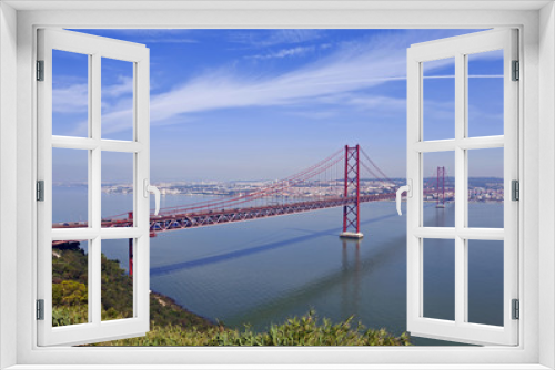 Fototapeta Naklejka Na Ścianę Okno 3D - Ponte 25 de Abril Bridge in Lisbon, Portugal. Connects the cities of Lisbon and Almada crossing the Tagus River. View from Almada with Lisbon across the river.
