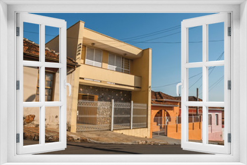 Fototapeta Naklejka Na Ścianę Okno 3D - Working-class colored houses and fences in an empty street on a sunny day at São Manuel. A cute little town in the countryside of São Paulo State. Southeast Brazil.