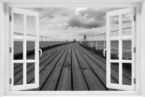 Fototapeta Naklejka Na Ścianę Okno 3D - Black and white image of two women walking along a seafront pier