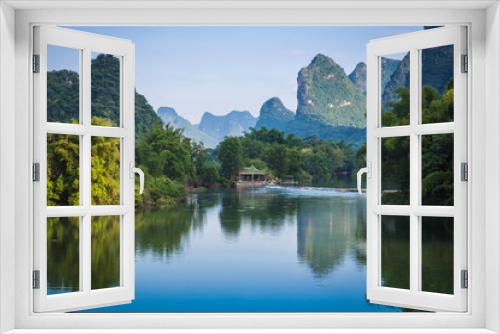 Fototapeta Naklejka Na Ścianę Okno 3D - Scenic view of Yulong River among green woods and karst mountains at Yangshuo County of Guilin, China. Yangshuo is a popular tourist destination of Asia.