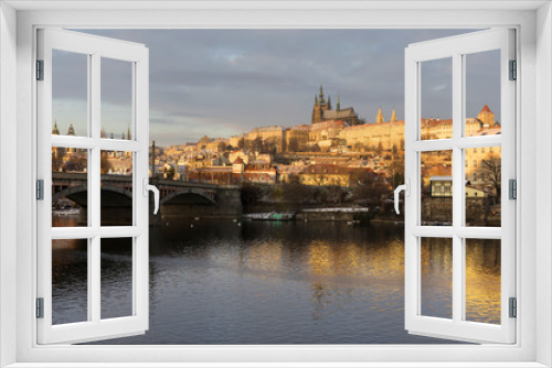 Sunny snowy early morning Prague Lesser Town with gothic Castle above River Vltava, Czech republic