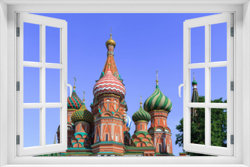 Domes of St. Basil's Cathedral against green trees and blue sky on a sunny summer morning