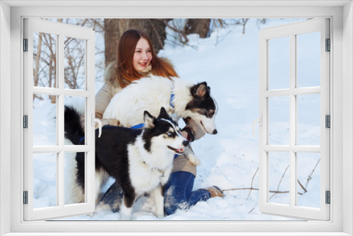 Fototapeta Naklejka Na Ścianę Okno 3D - A girl with long red hair plays with a Yakut husky in a snow park.