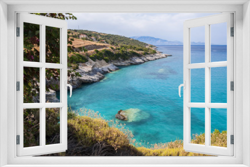 Fototapeta Naklejka Na Ścianę Okno 3D - A beautiful summer seascape of bay with crystal turquoise water and rocky coastline with some green flora. Colorful, vacation landscape of greek sea.