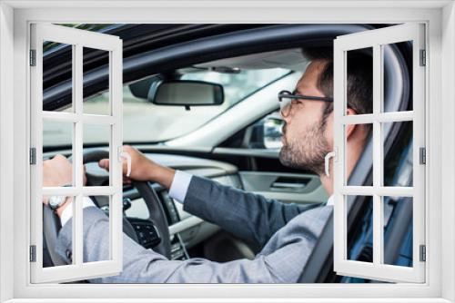 side view of businessman in eyeglasses driving car