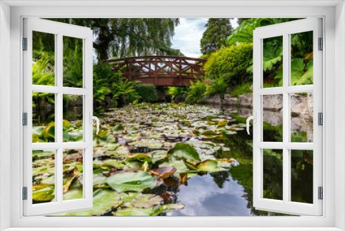 Fototapeta Naklejka Na Ścianę Okno 3D - Beautiful reflexion of a wooden bridge above  water can flowers and rocks on a smooth water surface.