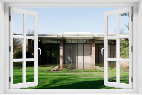 Fototapeta Naklejka Na Ścianę Okno 3D - Front facade of modern calm building over a water pond in front of a green lawn with relaxing people