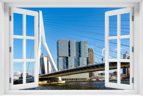 Fototapeta Naklejka Na Ścianę Okno 3D - Cityscape of Rotterdam at sunset with the Erasmus bridge in the foreground and high rise buildings of the financial district in the Dutch city in the background against a clear blue sky