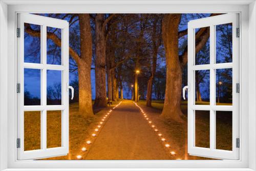 Fototapeta Naklejka Na Ścianę Okno 3D - Illuminated path in the park with beautiful candles flames glow