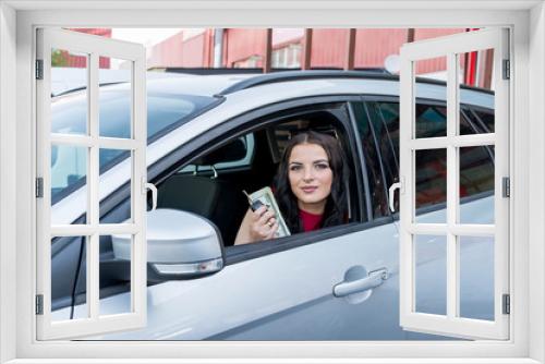 Woman showing dollar banknotes from car window