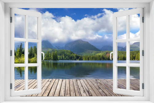 Fototapeta Naklejka Na Ścianę Okno 3D - Wooden path on alpine lake Strbske Pleso with reflection of mountains, sky and clouds in the calm water, High Tatras, Slovakia