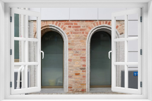 Fototapeta Naklejka Na Ścianę Okno 3D - Two plastic arched windows in a brick wall of an old restored house