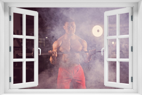 Fototapeta Naklejka Na Ścianę Okno 3D - Muscular young man lifting weights in gym