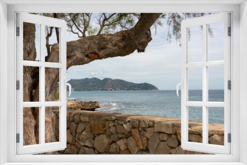 Fototapeta Naklejka Na Ścianę Okno 3D - View of the Mediterranean Sea and the hills from the beach promenade in the holiday resort Cala Millor on the Spanish Balearic island of Mallorca in front of a bright blue sky