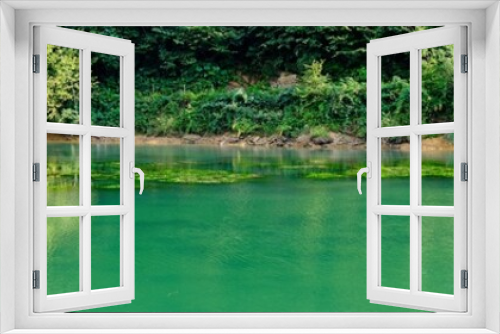 Fototapeta Naklejka Na Ścianę Okno 3D - Scorcio di un Lago di montagna verde smeraldo circondato da alberi. Vista panoramica