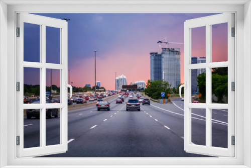 Fototapeta Naklejka Na Ścianę Okno 3D - Night traffic. Cars on highway road at sunset evening in typical busy american city. Beautiful amazing night urban view with red, yellow and blue sky clouds. Sundown in downtown.