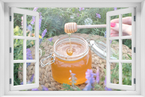 Fototapeta Naklejka Na Ścianę Okno 3D - a honey bank in a field with flowers. Spoon for honey.