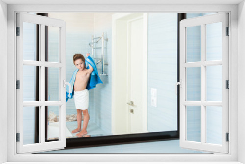 adorable healthy small child dry off his body with blue towel in morning bathroom