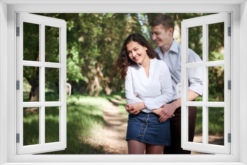 young couple walking in the forest, summer nature, bright sunlight, shadows and green leaves, romantic feelings