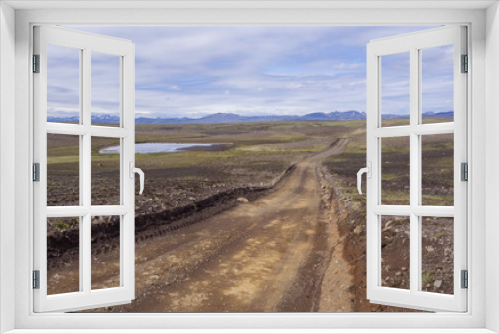 Fototapeta Naklejka Na Ścianę Okno 3D - dirt mountain road in abandoned green landscape at Nature reserve Fjallabak in Iceland with  snow covered rhyolit mountain range, blue sky white clouds