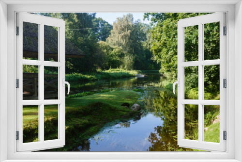 Fototapeta Naklejka Na Ścianę Okno 3D - an old building, a canopy with a straw roof and a river that flows along both sides; Rural landscape with fallen river and river; rest near the river in fresh air