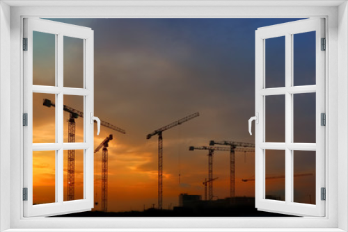Fototapeta Naklejka Na Ścianę Okno 3D - silhouette of construction and cranes in the evening on the sunset