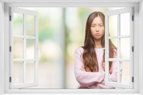 Young asian woman over isolated background skeptic and nervous, disapproving expression on face with crossed arms. Negative person.