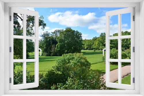 Fototapeta Naklejka Na Ścianę Okno 3D - Path to the hill in a beautiful city Park past the trees and smoothly trimmed lawn with green grass on a Sunny summer day on background of blue sky with white cloud. Top view