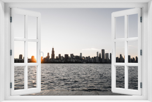 Fototapeta Naklejka Na Ścianę Okno 3D - Chicago skyline picture during beautiful sunset with building silhouettes and rippling waves of Lake Michigan water in the foreground