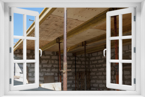 Fototapeta Naklejka Na Ścianę Okno 3D - view of the wooden formwork with metal holders, which will be filled with the overlap between the floors in the country house under construction from the foam block