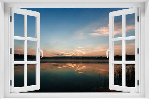 Fototapeta Naklejka Na Ścianę Okno 3D - Beautiful, red dawn on the lake. The rays of the sun through the fog. The blue sky over the lake, the morning comes, the sky is reflected in the water.