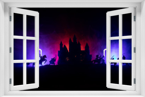 Fototapeta Naklejka Na Ścianę Okno 3D - Medieval battle scene with cavalry and infantry. Silhouettes of figures as separate objects, fight between warriors on dark toned foggy background with medieval castle. Night scene. Selective focus