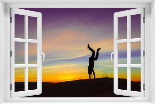 Fototapeta Naklejka Na Ścianę Okno 3D - Silhouette of woman doing hand stand on sand dune during the sunset