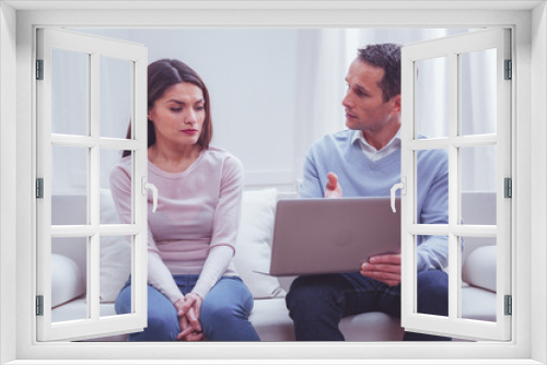 Pieces of advice. Adorable long haired concentrated woman being attentive while experienced psychologist using a laptop and sharing workable solutions against life problems