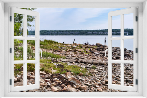 Fototapeta Naklejka Na Ścianę Okno 3D - Distant view of the condominiums at Stockton Springs Harbor in Maine with rocky coastline in the foreground.