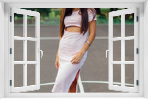 Charming brunette female dressed in a pink dress posing on the basketball court.