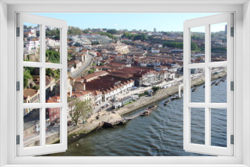 Fototapeta Naklejka Na Ścianę Okno 3D - Landscape from the bird's eye view of buildings and streets of the city of Porto on the banks of the river against the blue sky.