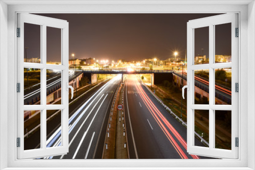 Fototapeta Naklejka Na Ścianę Okno 3D - DIFFERENT TRAFFIC LIGHTS OF VEHICLES IN A MOTORWAY WITH THE LIGHTS OF THE CITY AT THE END