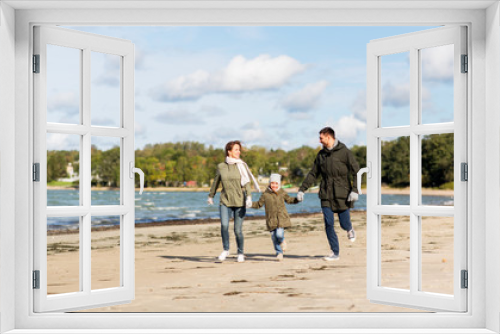 Fototapeta Naklejka Na Ścianę Okno 3D - family, leisure and people concept - happy mother, father and little daughter running along autumn beach