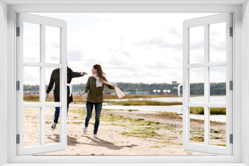 Fototapeta Naklejka Na Ścianę Okno 3D - love, relationship and people concept - smiling couple running along autumn beach and holding hands