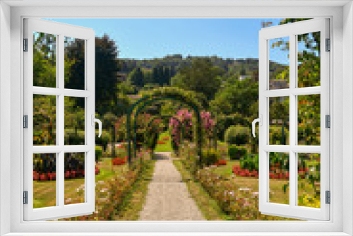 Fototapeta Naklejka Na Ścianę Okno 3D - Veduta di un giardino fiorito d'estate con archi, sentieri, aiuole e collina sullo sfondo, Villa Pallavicino, Stresa, Lago Maggiore, Italia