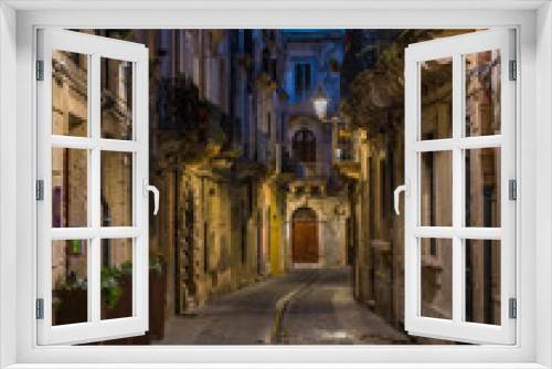 Fototapeta Naklejka Na Ścianę Okno 3D - A picturesque road in Siracusa old town (Ortigia) at night. Sicily, southern Italy.