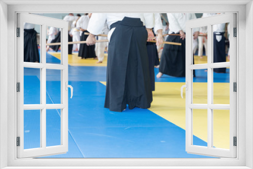 People in kimono practice Aikido with wooden jo on martial arts weapon training seminar