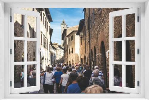 Fototapeta Naklejka Na Ścianę Okno 3D - Crowd of tourists people walk together stretched and with the street full in San Gimignano near Siena in Tuscany, Italy. Vacation and culutre in a medieval city full of history