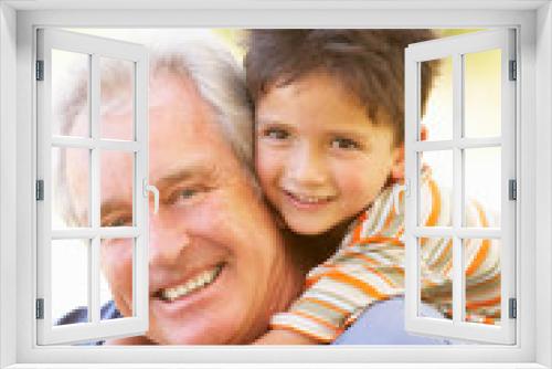 Grandfather Giving Grandson Ride On Back In Park