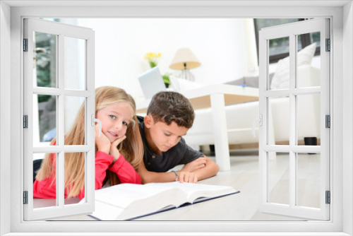 two young happy kids brother and sister together having fun at home reading encyclopedia book