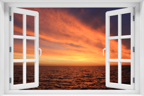 Fototapeta Naklejka Na Ścianę Okno 3D - Sky Nature View of Sunset Over Calm Sea Water with Vibrant Orange Cloudscape. Beautiful Sky Background at Sunset or Sunrise, Dusk and Dawn Panoramic Skyline View with Still Water on Summer Season Day