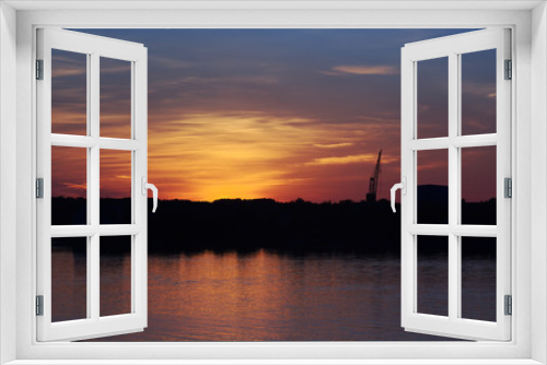 Fototapeta Naklejka Na Ścianę Okno 3D - The silhouette of a crane and an industrial building at sunset
