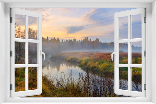 Fototapeta Naklejka Na Ścianę Okno 3D - Foggy autumn landscape with small forest river.Autumnal hazy early morning.Twilight.Calm stream of river flowing between the woods and meadows covered by fog.Colorful clouds in sky at sunrise.