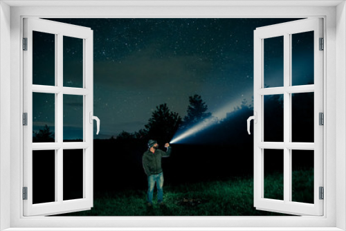Fototapeta Naklejka Na Ścianę Okno 3D - Man searching with flashlight in outdoor by night